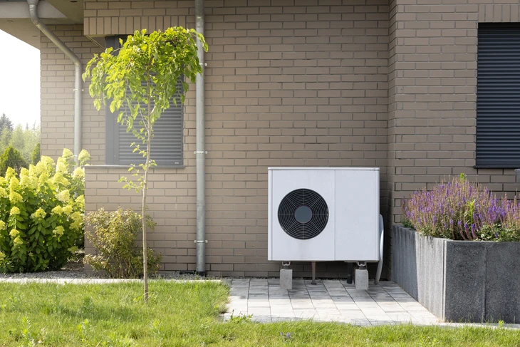 Extérieur résidentiel moderne avec pompe à chaleur air-eau installée sur terrasse pavée