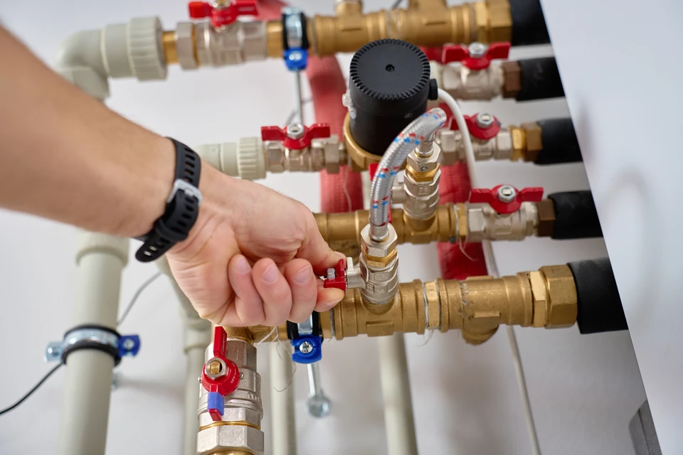 Les mains du plombier installent un radiateur avec deux clés